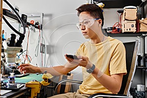 skilled asian technician in goggles holding