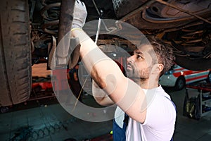 Skilled auto mechanic is performing customer automobile checkup