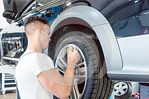 Skilled auto mechanic replacing the rims of a car in a trendy repair shop