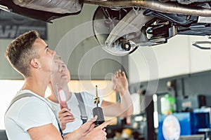 Skilled auto mechanic replacing the shock absorbers of a car in workshop