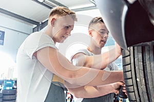 Skilled auto mechanic working together with his colleague