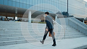 Skilled business man walking up stair while holding bag in the hand. Exultant.