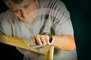 Skilled carpenter man sanding wood frame