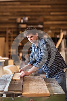 Skilled carpenter working in his woodwork workshop, using a circular saw