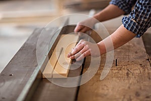 Skilled carpenter working in his woodwork workshop, using a circular saw