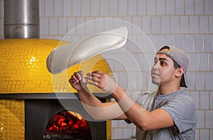 Skilled chef preparing dough for pizza rolling with hands and throwing up. The chef tosses the pizza dough into the air photo