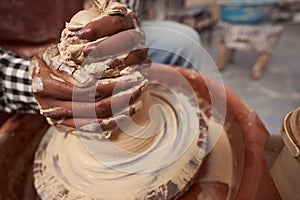 Skilled craft artist throwing pottery in his studio