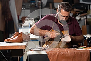 Cobbler at work repairing a leather shoe in a busy workshop