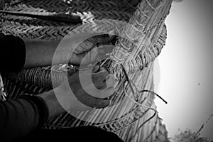 Skilled craftsman working manually a detailed bamboo wood armchair with his fingers and tools