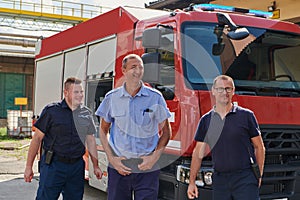 A skilled and dedicated professional firefighting team proudly poses in front of their state of the art firetruck