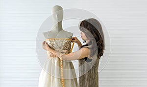 A skilled dressmaker taking precise measurements of a dress on a mannequin, exhibiting utmost care and detail