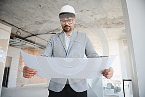 Skilled engineer analyzing blueprints at construction site