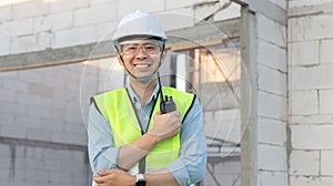 Skilled engineer inspects factory construction and uses a radio to chat with colleagues working on the field