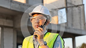 Skilled engineer inspects factory construction and uses a radio to chat with colleagues working on the field