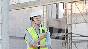 Skilled engineer inspects factory construction and uses a radio to chat with colleagues working on the field