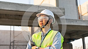 Skilled engineer inspects factory construction and uses a radio to chat with colleagues working on the field