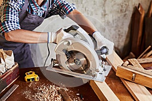 Skilled female carpenter using a circular saw. Woman worker in the carpenter workroom renovation. Small business concept