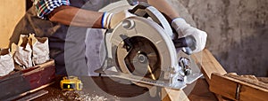 Skilled female carpenter using a circular saw. Woman worker in the carpenter workroom renovation. Small business concept
