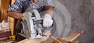 Skilled female carpenter using a circular saw. Woman worker in the carpenter workroom renovation. Small business concept