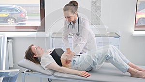 Skilled female doctor conducts abdominal examination on young female patient in clinic