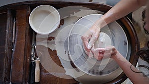 skilled female potter is working with pottery wheel in workshop, top view