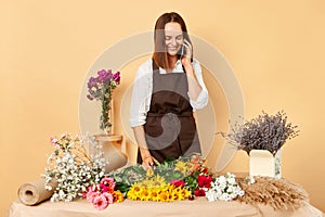 Skilled florist arranges. Bustling flower market. Vibrant floral arrangements. Busy woman florist talking via smartphone making