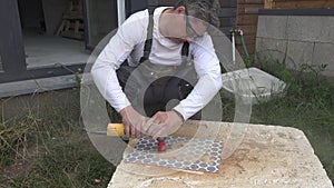 Skilled guy cutting holes in tile using an angle grinder with diamond crown