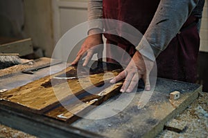 Skilled hands of a craftsman work meticulously on a piece of wood, showcasing the art of woodworking and the care that