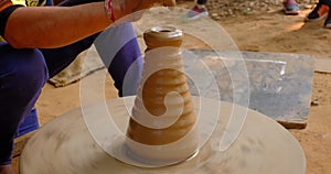 Skilled hands of potter shaping the clay on potter wheel and sculpting clay pot jar. Shilpagram, Rajasthan, India