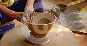 Skilled hands of potter shaping the clay on potter wheel and sculpting clay pot jar. Shilpagram, Rajasthan, India