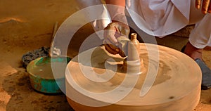 Skilled hands of potter shaping the clay on potter wheel and sculpting clay pot jar. Shilpagram, Rajasthan, India