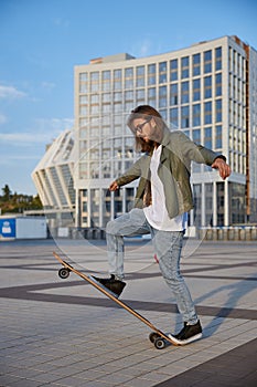 Skilled hipster guy making stunt on skateboard riding fast