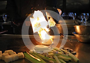 Skilled japanese cook cooking at hibachi grill, tasteful asian food. Fried rice, vegetables, and noodles.