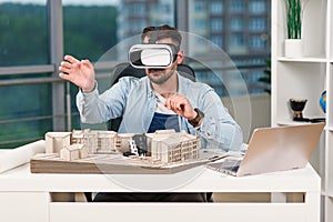 Skilled male architect reviewing an architectural project with augmented reality glasses in design office.