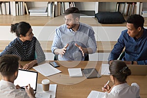 Skilled male manager talking to diverse business people at meeting