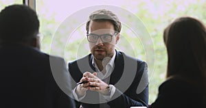 Skilled male manager wearing suit, holding negotiations with coworkers.