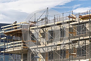 Skilled man standing on scaffolding near incomplete building