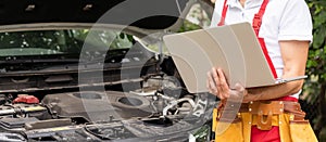 Skilled mechanic using a laptop computer to check a car engine