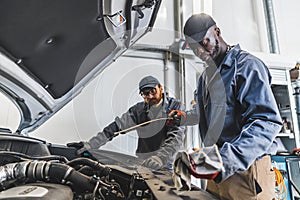 Skilled mechanics repairing a car engine using tools in modern auto repair shop