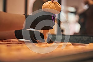 Skilled pastry chef using syringe with icing while making macarons