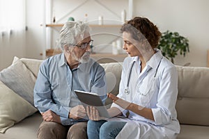 Skilled physician showing test results on tablet to old patient.