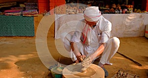 Skilled professional potter throwing the potter's wheel and shaping clay ware: pot, jar in pottery workshop in India