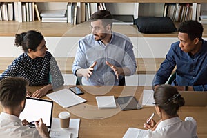 Skilled male manager talking to diverse business people at meeting photo