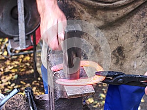 Skilled smith man striking a red hot horseshoe on the anvil