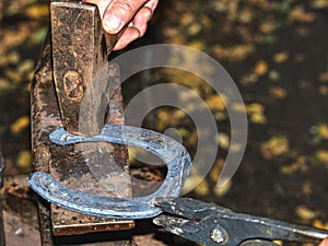 Skilled smith man striking a red hot horseshoe on the anvil