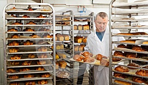 Baker arranging trays with bakery products on trolley
