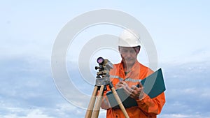 Skilled surveyor fixes dumpy level on brown wooden tripod