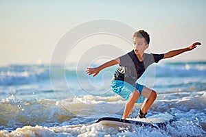 Skilled teenager riding surfboard and balancing a long wavy sea.