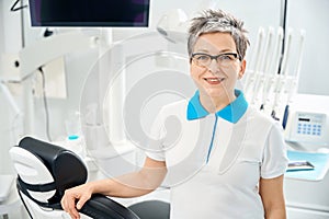 Skilled woman dentist standing in her office, offering high qualified care