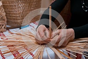 Skilled woman plaits a straw bag at ethnographic master class, traditional craft art at ethnographic master class